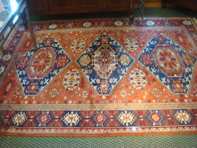 Vintage Wool Rust Colored Geometric Pattern Area Rug:: Vintage Wool Rust Colored Geometric Pattern Area Rug: Dark Blue & Light Blue Accent Colors on Rust Ground w/Biege Border & Fringe. 8'8" X 6'8". (300-500)