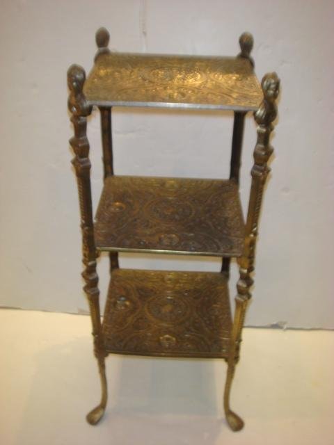 Three Tiered Ornate Victorian Brass Table Stand:: Three Tiered Ornate Victorian Brass Table Stand: Table Stand with Repetitive Embossed Design on all Levels. Trays include a Circular Medallion and Four Faces. Maiden Head Finials Cap the Top of Each L