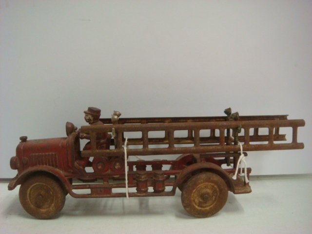 HUBLEY AHRENS FOX 1940's Iron Ladder Truck:: HUBLEY AHRENS FOX 1940's Iron Ladder Truck: Red Cast Iron Fire Truck with Driver, Two Pressed Steel Ladders, Cast Iron Disc Wheels and Original Label Still Visible on Hood. Some Rust. 9"L. (150-200)