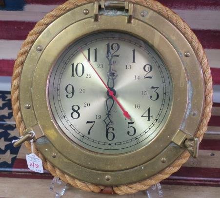 BEY-BERK International Quartz Port Hole Clock:: BEY-BERK International Quartz Port Hole Clock: Brass Port Hole Front on Wooden Base with Rope Trim. Metal Face with Arabic Numerals. Second Hand. 13"D. Quartz Movement. (160-240)