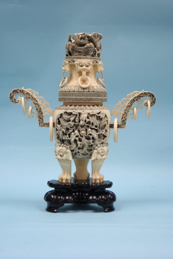 An important Chinese carved ivory incense burner.: An important Chinese carved ivory incense burner. Oval form body raised on three lion's paw feet, surface carved and stained with winding dragons, wing shaped handles with loose rings. Cover carved wi