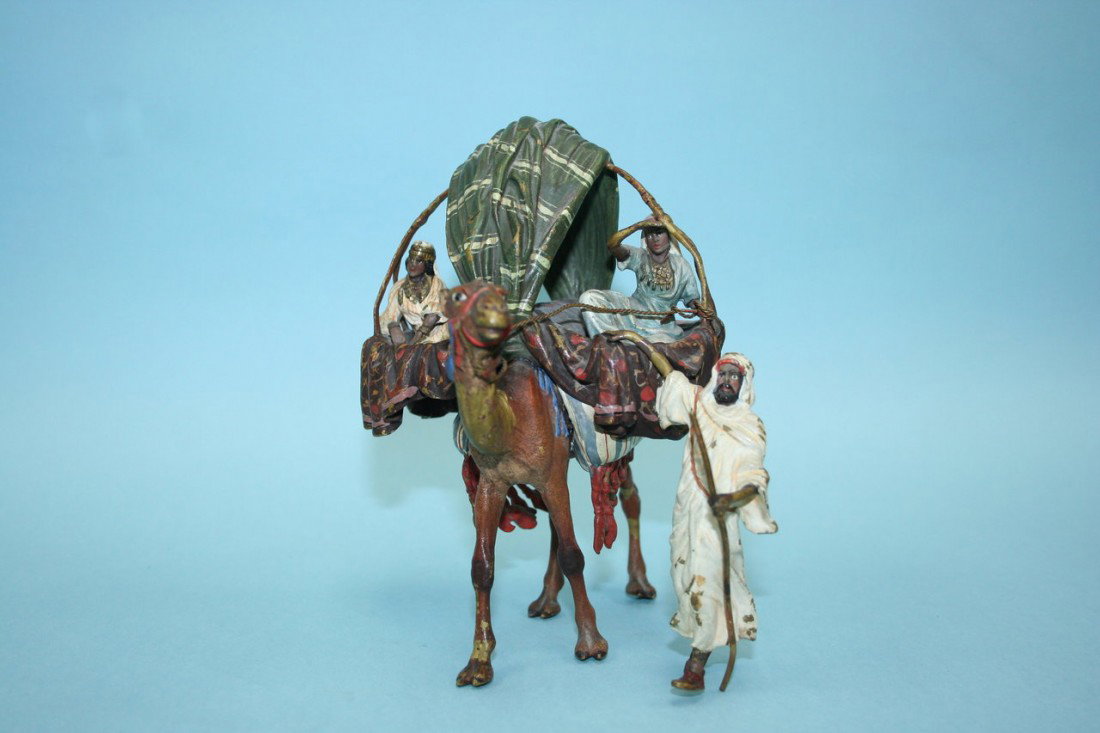 FRANZ BERGMAN - An antique Austrian polychrome pati: FRANZ BERGMAN - An antique Austrian polychrome patinated figural group of a camel driver, his camel fitted with twin baskets carrying two oriental beauties. 5 3/4" high. Stamped marks.