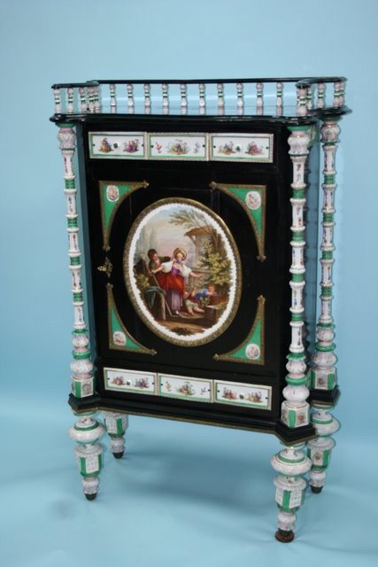 An antique German porcelain mounted ebonized salon: An antique German porcelain mounted ebonized salon cabinet. Front and back mounted with four handpainted porcelain columns, rectangular door inset with a large oval porcelain plaque and additional por