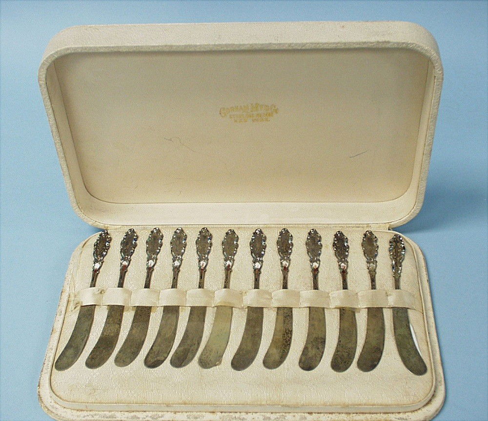 A set of 12 gilt and enamelled sterling silve: A set of 12 gilt and enamelled sterling silver butter knives by Gorham, New York. Each fully hallmarked. In custom made presentation case. Circa 1900.