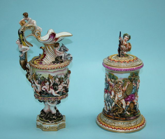 A lot of 2 pieces, an Italian Capo-di-Monte covered: A lot of 2 pieces, an Italian Capo-di-Monte covered urn and a matching ewer. Urn with tapered columnar body relief decorated with a battle scene. Cover with putto handle, 12" high. Hallmarked undersid