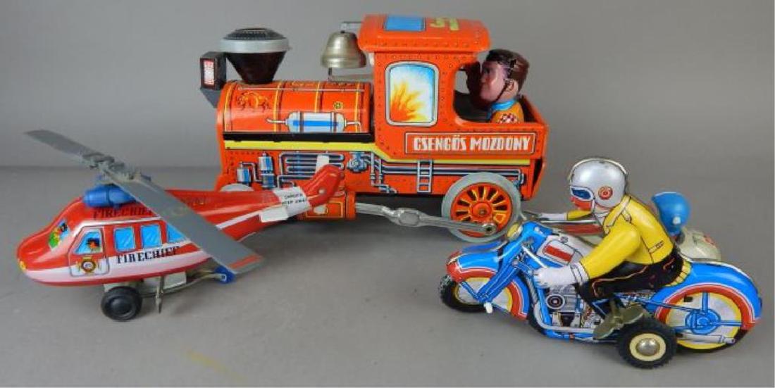 Helicopter, Train and Motorcycle Tin Toys: Fire chief Helicopter with key 12", Csengos Mozdony battery operated train 11" and Motorcycle side car with key 7 1/2". Estimate $200 - $300. Starting bid $30.