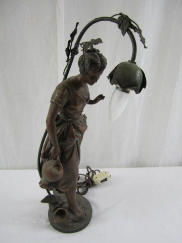 A32-3 WOMAN FIGURE TABLE LAMP: Statue in white metal of a woman holding a broken water jug mounted on a white metal lmp base. Light fixture extends from the base behind and over the head of the statue and is entwined with a vine an