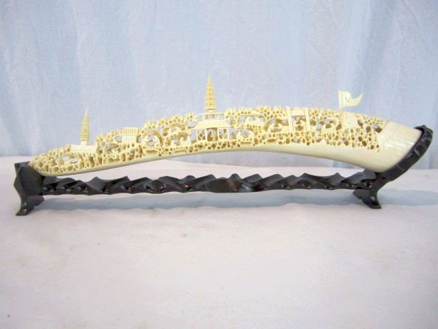 A45-29 CARVED IVORY TUSK WITH VILLAGE SCENE: On wood base. Good condition. Measures 17 1/2". Estimate $1,500 - $2,500