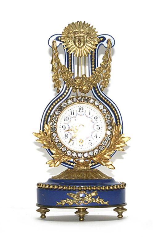 F60-96 FRENCH TIFFANY & CO LYRE CLOCK: Blue cast metal frame with applied ormolu sunburst, garland and floral decoration. Marked Tiffany & Cie on porcelain dial with painted floral swags. Key wind movement, key with clock. Movement marked