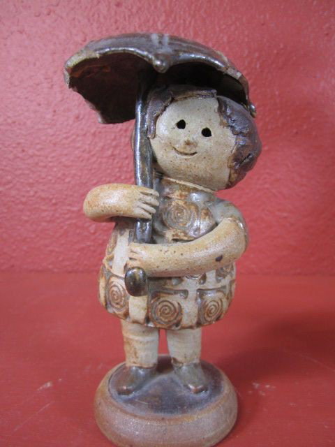 C15-5 SIGNED "CLIFF STEWART" POTTERY SCULPTURE: "Girl With Umbrella" signed "Cliff Stewart 1964." From a private collection. Umbrella has been repaired. Measures 6 1/2" tall. The artist's work is currently on exhibit at the J. Paul Getty sponsored 