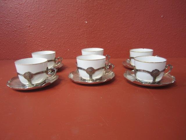 A1-4 CHRISTOFLE GALLIA SET: Silver plate coffee/teacup , the set includes 6 porcelain cups, 6 cup holders and 6 saucers. Cups measure 2 1/2" tall and saucers 5 1/2" diameter. One cup has been repaired. Estimate $300 - $500 Start
