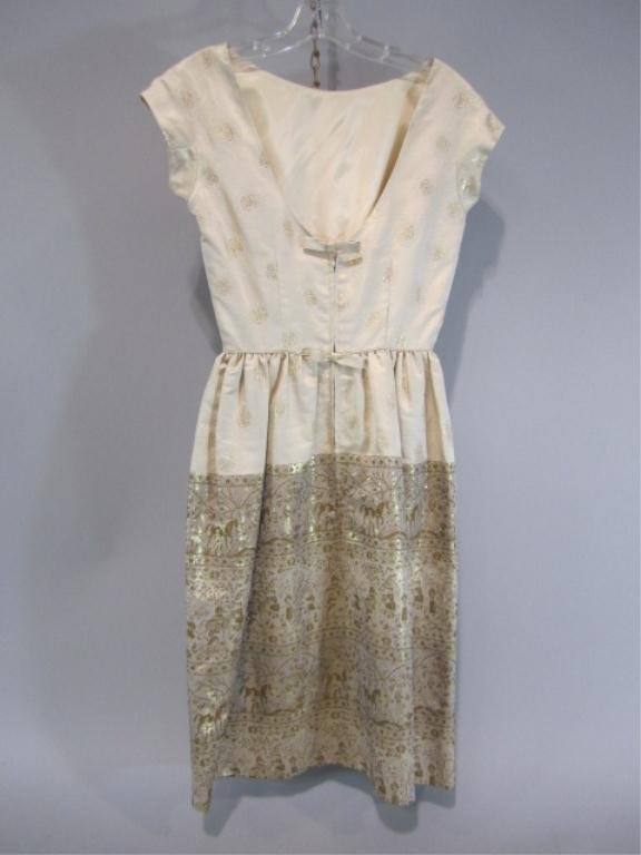 E14-4 VINTAGE 1960s COCKTAIL DRESS BY FRANK STARR: Sleeveless v-back cream colored cocktail dress with gold metallic brocade trim. Approximate size 8. Estimate $150 - $300 Starting Bid $50
