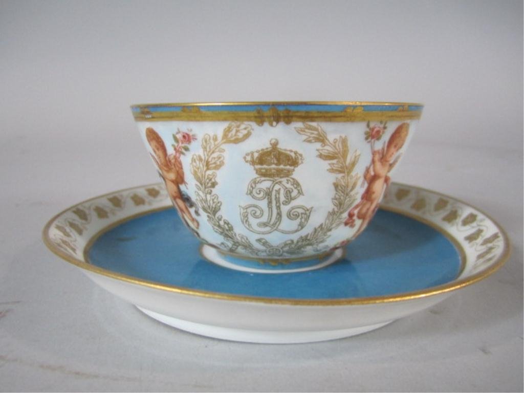 H70-14 SEVRES PORCELAIN CUP & SAUCER: Cupid with crown. Made for one of the Kings Chateau's. Circa 1840. Cup measures 1 7/8" and saucer 5 1/2" diameter. Estimate $200 - $400 Starting Bid $50