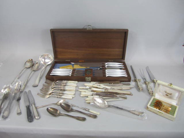 H25-37 COLLECTION OF UTENSILS: Including silver plate ladle, spoon and fork, set of Towle stainless knives, assorted Christofle flatware, Christofle demi spoons in a box, and mother of pearl forks and knives set. Good condition. Es