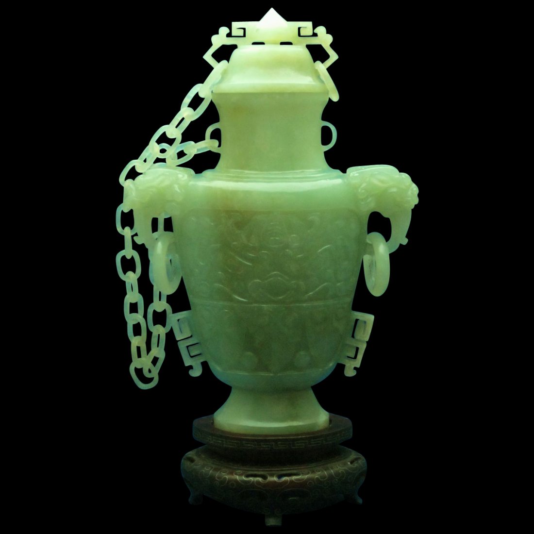 FINE CELADON JADE URN W/ CHAIN ON SILVER WIRE STAND: The carved vase with Taotie masks and beastly heads, and multiple rings hanging from the body and lid. The lid is attached to the vase with a chain carved from a single piece of jade. Stands on the or