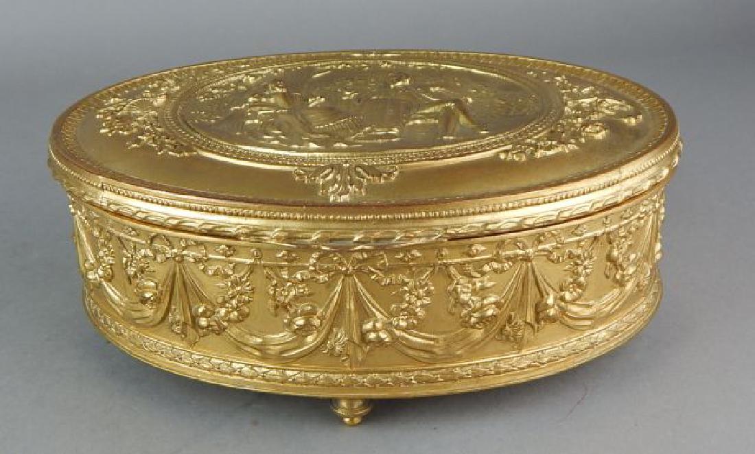 Dore Bronze Oval Box: Decorated with flowers, swag ribbons and bows, hinged lid has figural scene, four feet and fabric inside, signed JB 27 33 on bottom and measures 3 1/2" x 8 1/2" x 6". Estimate $600 - $800 Starting Bid