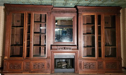 French Louis XVI Bookcase Wall in Oak with Fireplace: Magnificent wall of French Louis XVI style bookcases in oak with a fireplace in the center. The doors have classical carvings of urns, cornucopia and vines. The doors are surrounded by fluted pilaster