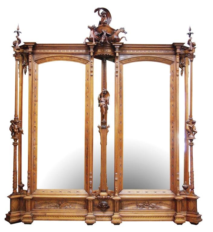 Antique Monumental Highly Carved Walnut Armoire: Monumental carved walnut armoire from France depicting a center figural carving of a warrior atop driving a chariot with horses. Mythological detailed panels and carvings, columns surrounded by putti,