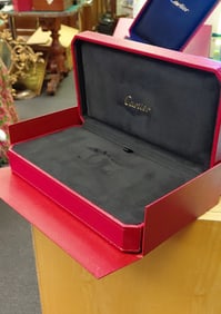 Classic high end jewelry Cartier watch case in their typical red and gold decor.