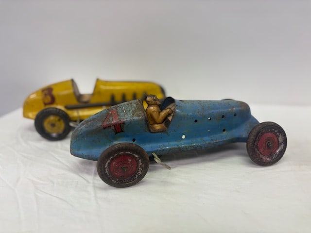 Pair of pressed steel windup race cars: One yellow ad the other is blue with a driver.