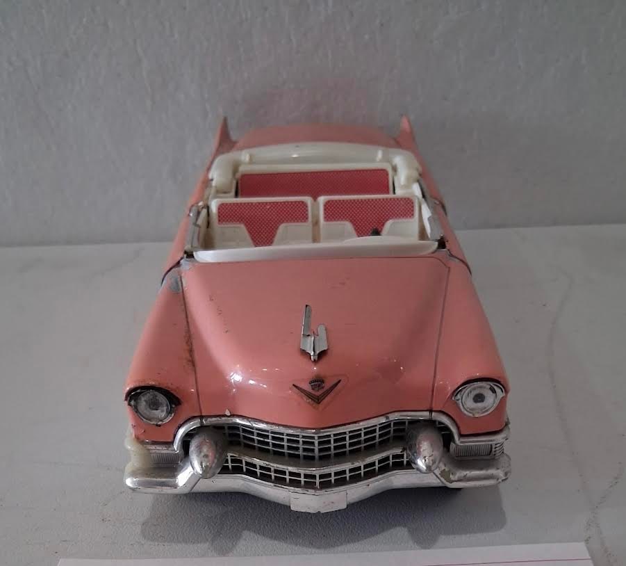 Pink 1955 Chevy Convertible Diecast Model Car: Pink and white 1955 Chevy-style convertible diecast model car. Approx. 2" H x 10.5" D x 4" W per card. Pre-owned/display condition with intentional or age-related paint wear.