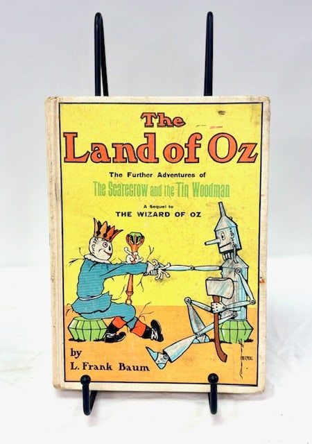 L. Frank Baum “The Land of Oz” Illustrated Book: Vintage copy of “The Land of Oz” by L. Frank Baum, featuring illustrated front cover artwork with the Scarecrow and Tin Woodman. The cover reads “The Further Adventures of The Scarecrow and 