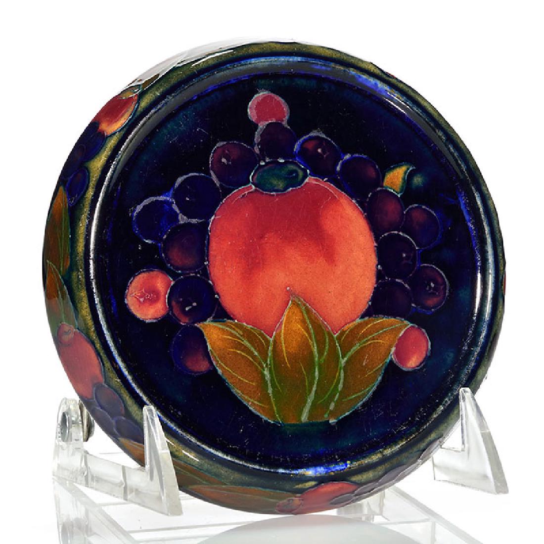 Moorcroft Pomegranate trivet, 5 1/2 inches diameter: Moorcroft Pomegranate 5 1/2 inch diameter trivet. Painted William Moorcroft signature in blue and impressed MOORCROFT, 285 and Made in England. There is fine overall crazing.