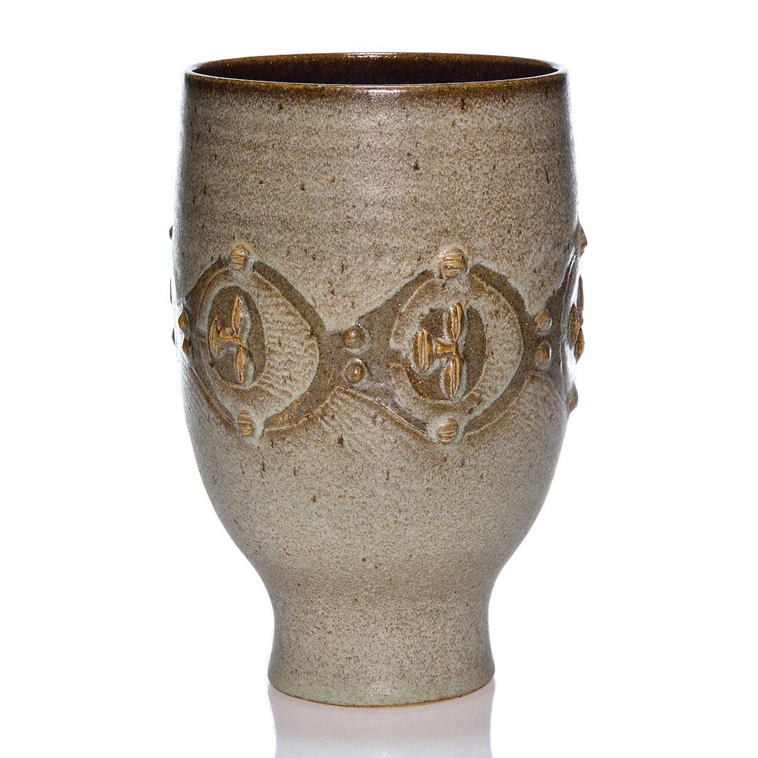 Edwin and Mary Scheier vase with faces, 10 1/4",: Edwin and Mary Scheier vase with a chain link band of sleepy faces that appear to be viewing from astronaut helmets covered by a speckled gray glaze over walnut brown. Measures 10 1/4 inches by 6 1/4