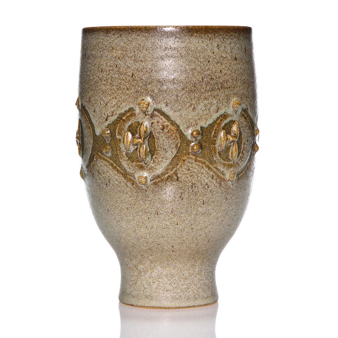 Edwin and Mary Scheier vase with faces, 10 1/4": Edwin and Mary Scheier vase with a chain link band of sleepy faces that appear to be viewing from astronaut helmets covered by a speckled gray glaze over walnut brown. Measures 10 1/4 inches by 6 1/4