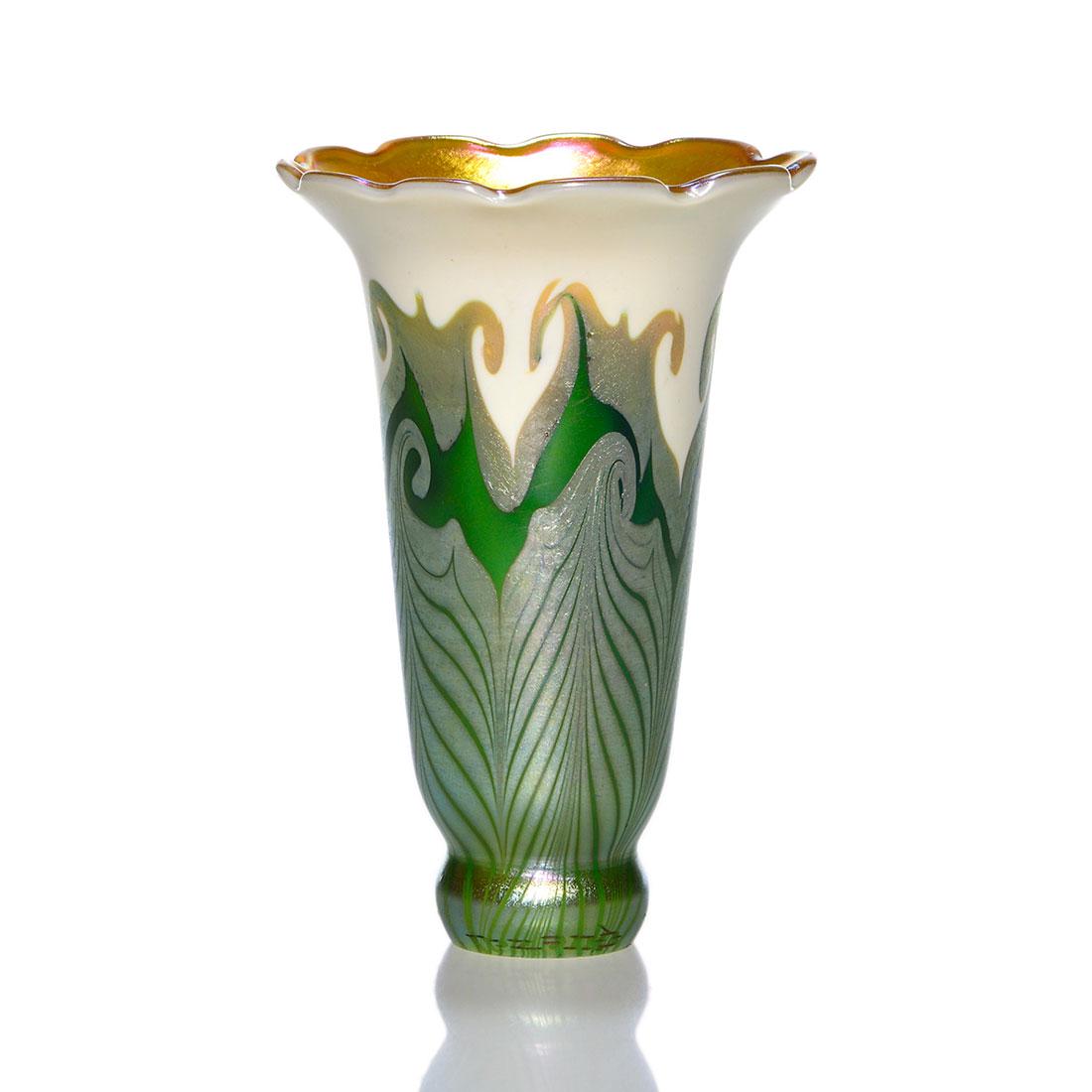 Quezal lily shade, design, Roberts #244, 4 1/2": Good Quezal lily shade partially cased in emerald green upon which a double design was pulled in silvery gold over an oyster white. The petal scalloped edge reveals a bright golden interior having mag