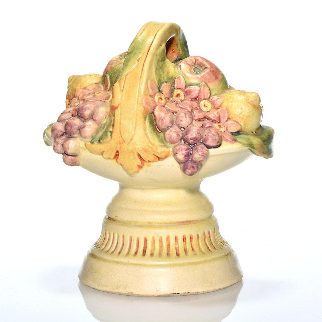 Weller Fruit & Flower Basket doorstop, 9 1/4”: Large Weller doorstop in the form of a basket overflowing with colorful fruit and flowers. Height 9 1/4 inches. Impressed Weller on the bottom. There is fine overall crazing.