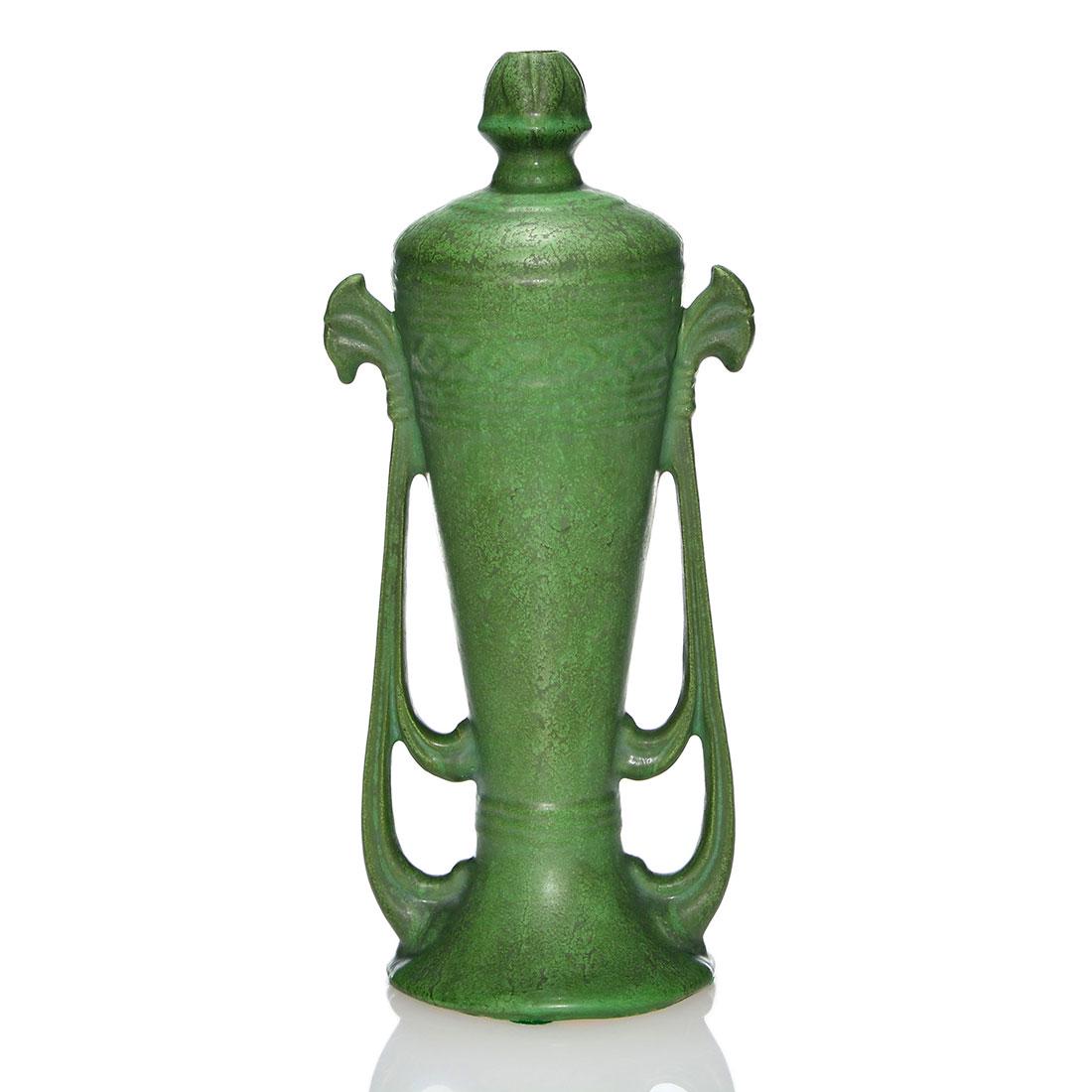 Roseville Egypto lamp vase, 12”, mat green: Roseville Egypto lamp vase covered in a frothy green mat glaze. Marked on the bottom with the Rozane Ware Egypto wafer. There is minor grinding roughness and a bruise at the base. Height is 12 inches.