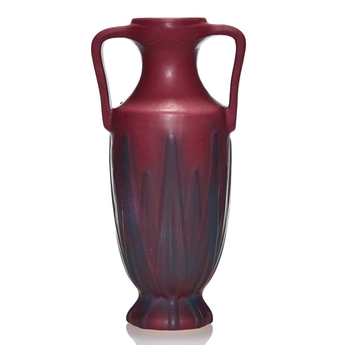 Van Briggle Mulberry handled urn, 13 3/8”, leaf: Van Briggle double handled urn revealing yucca leaves under a Mulberry Glaze. Height 13 3/8 inches. Incised Van Briggle, U.S.A. with the factory logo. Minor glaze bursts. Tiny glaze pull below the foo