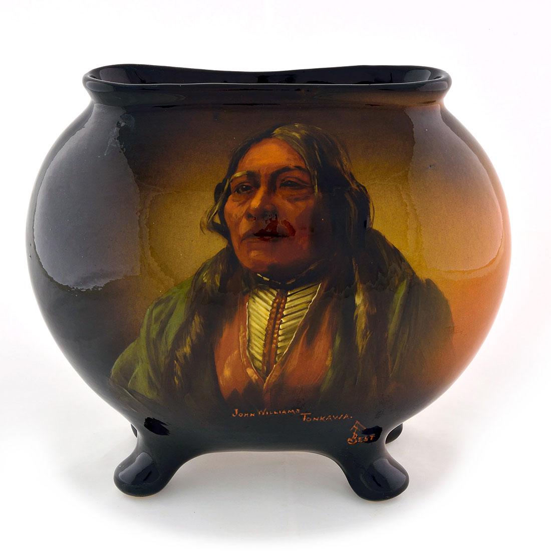Owens Utopian pillow vase, Indian portrait, Best, 8: Owens Utopian pillow vase on four bun feet bearing the portrait of a Native American John Williams Tonkawa done by Anna Fulton Best who added her monogram and the name of the sitter in orange slip. Im