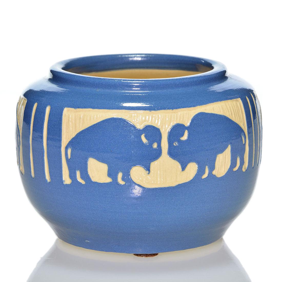 Carved UND vase, Bison, Julia Mattson, 3 3/8” by: Deeply carved UND vase with 3 sets of bison done by Julia Mattson. The vase is covered in a semi-gloss blue slip which is carved back to the cream colored clay. Marks include the circular UND ink stam