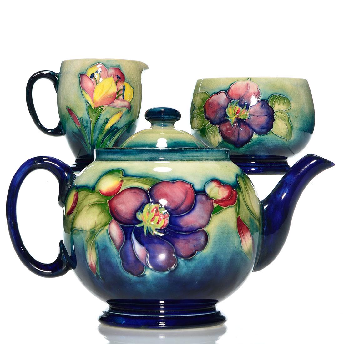Moorcroft Clematis-Crocus 3 pc. tea set, tallest 6: Moorcroft footed tea set consisting of a 6 inch tea pot and a 2 3/4 inch open sugar in Clematis pattern and a 3 1/4 inch creamer in the Crocus pattern. The tea pot and sugar are impressed made in Engl