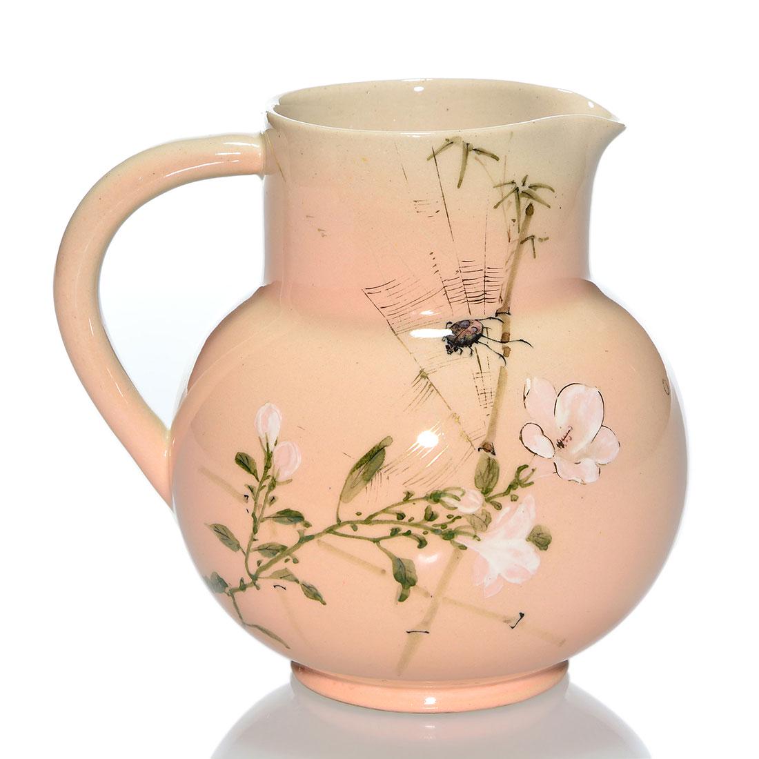 Rookwood Cameo pitcher, beetle in web, 1887, 5: Unusual Cameo glaze pitcher featuring apple blossoms in which a spider web has trapped a small beetle. Done in 1887, the piece bears the company logo, which indicates the date, shape number 15 and W 7