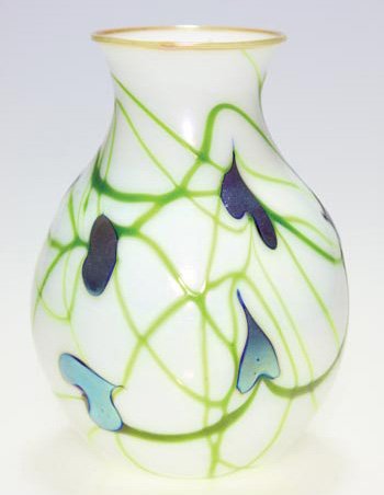 Charles Lotton vase, white, blue leaves, 6 1/4": Early Charles Lotton white opal vase decorated with iridescent blue foliage attached to moss green vines, pale amber wrapping the rim. Height 6 1/4 inches. Engraved "Charles Lotton, 1973" beneath. Too
