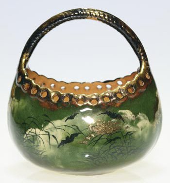 Rookwood basket, bats, 1882, AH, 5": Basket decorated with bats flying across a cloudy sky with Orienetal vegetation visible and enhanced with fired on gold, the work of Albert Humphreys on shape 33 C. Impressed Rookwood 1882 and incised
