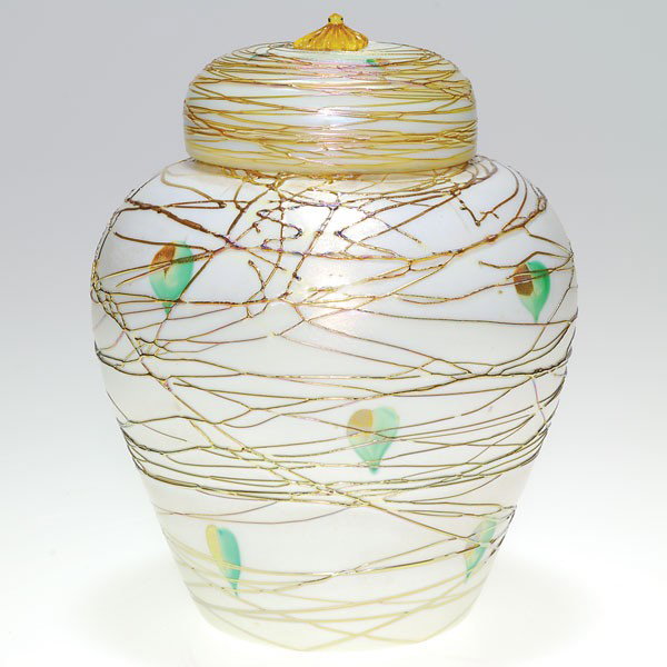 Durand covered jar, decorated, gold threading, 7 1: Durand temple vase with cover displaying a weave of golden threads enclosing green and gold foliage scattered over an opal white surface. Height 7 1/2 inches. An amber rosette tops the cover. The vase