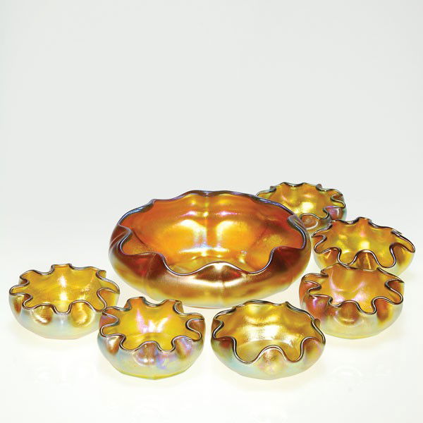 Tiffany master salt+6 small salts, gold, 1 3/4"X5: Tiffany master bowl accompanied by six individual salt cellars. The set are iridescent gold and have ribbed bodies and scalloped rims. The master salt measures 1 3/4 inches by 5 1/4 inches. The indivi