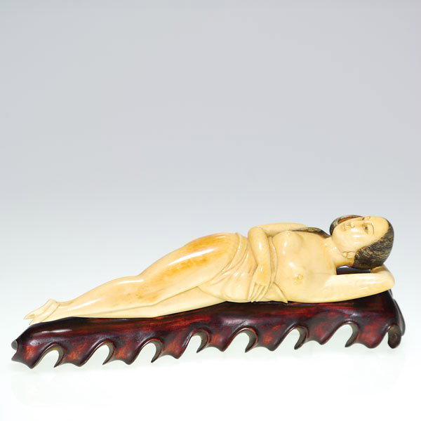 Ivory reclining lady, carved wood stand, 9 1/2": Beautiful ivory carving of a doctor's model of a nude lady. She lies in a half twist position with one arm supporting her head, her midsection draped in cloth poised upon a carved wood base. Her black