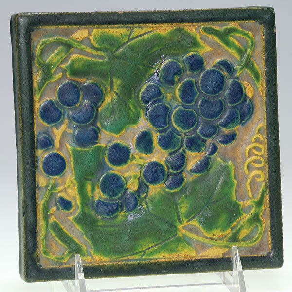 Rookwood 6" trivet, grapes, mat, shape 1683.: Tea tile depicting a bunch of luscious, blue grapes, just waiting to be picked from their vine. Impressed with the Rookwood logo, the 1909 date of manufacture and the shape number 1683. No crazing wit