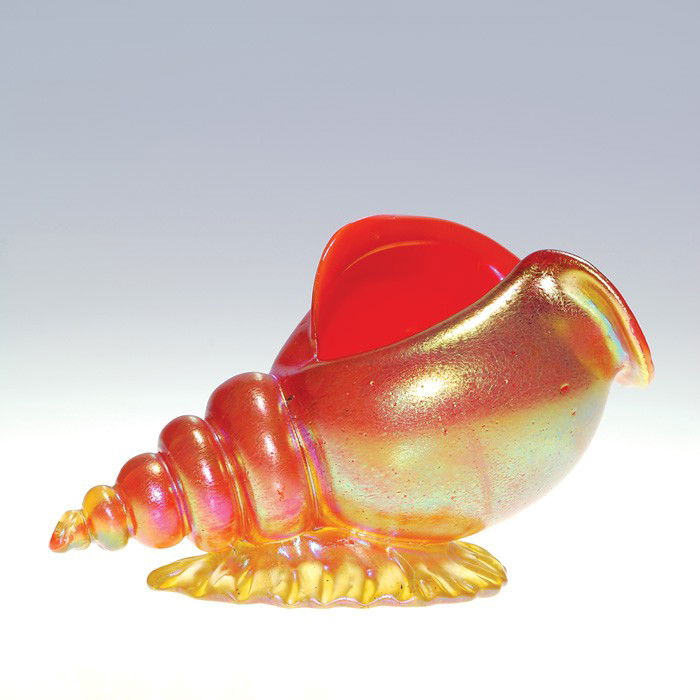 Loetz conch shell, orange & gold, 4 1/4"X7 1/2": Beautiful Loetz conch shell that has came to rest upon a placid golden wave. The mollusk displays a nice iridescent gold surface and is encased with a bright orange interior. Height 4 1/2 inches, leng