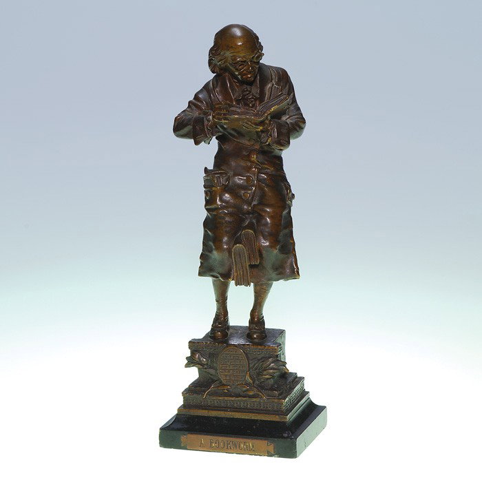 Carl Kauba bronze "A Bookworm" 10 1/8": Early Carl Kauba bronze entitled "A Bookworm" showing a bespectacled man paging through a tome while his pockets are stuffed with more books and two large volumes are held between his knees. Signed "C