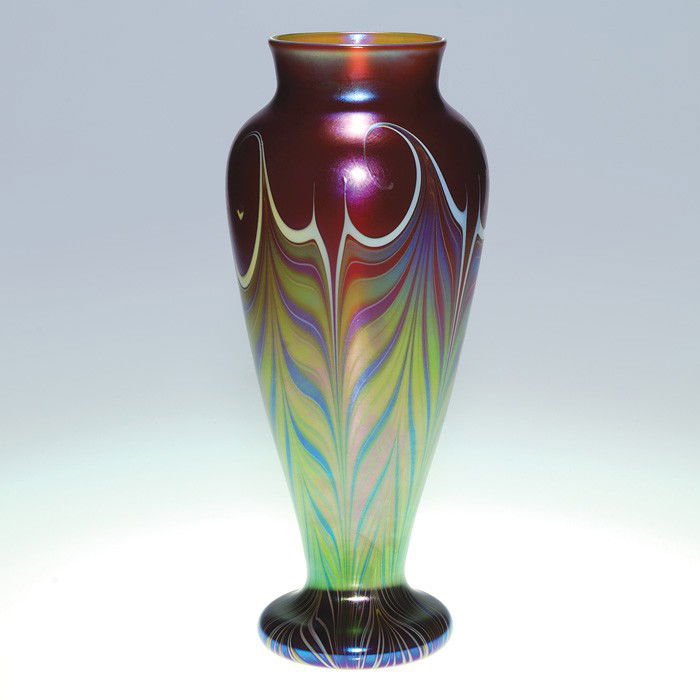 Orient & Flume vase, plumes, 12 3/4", signed, '82: Tall Orient & Flume vase displaying feathery plumes combed from the foot towards the rim with curled edges tipped in white. The plumes are bright with colorful iridescence and sprawl over a pretty red