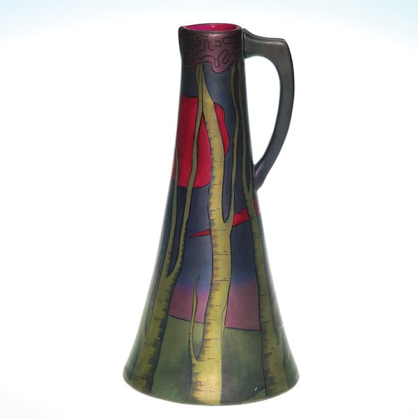 Fine Swastica Keramos pitcher, Zsolnay like color: Good Swastika Keramos pitcher, the tapered body displaying tall trees stark against a landscape at nightfall in Zsolnay-like color. Height 10 3/4 inches. The raised logo is beneath the base. Handsome 