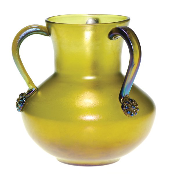 Loetz “Bronce Glatt” 3 handled vase, prunts: Loetz “Bronce Glatt” vase adorned by a trio of handles each fastened by applied floral ornaments. Height 6 inches. This quality glass was produced for Max Emmanuel of London. Handsome excellent co