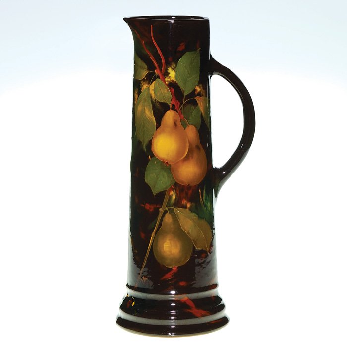 Weller Aurelian tankard, pears, signed IB, 17”: Weller Aurelian tankard decorated with pears, perhaps the work of Lisabeth Blake. The 17 inch tall vessel is marked on the bottom Aurelian Weller K 38 7 and has been initialed by the artist on the sid