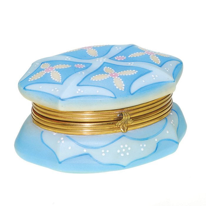 Nakara jewelry casket, blue, floral, 3”X5 1/2”: Oval Nakara jewelry casket attractively decorated in two shades of blue with four tan florets and adorned with white enamel enhancements. Height 3 inches by 5 1/2 inches in length. Stamped “Nakara C